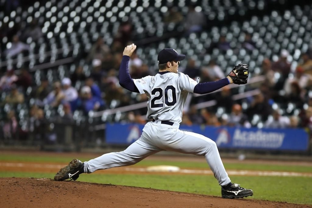 Baseball player pitching on field during a game, showcasing athletic action and focus.